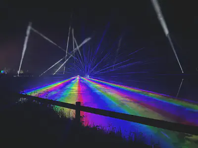 Photo of multicoloured beams of light across a dark lake