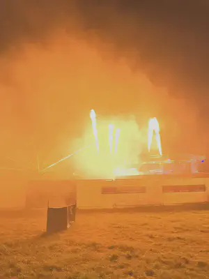 Photo of jets of flame above a stage in a field