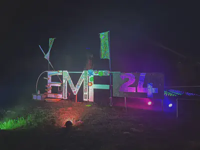Photo of a sign at night in various colours, reading EMF 24